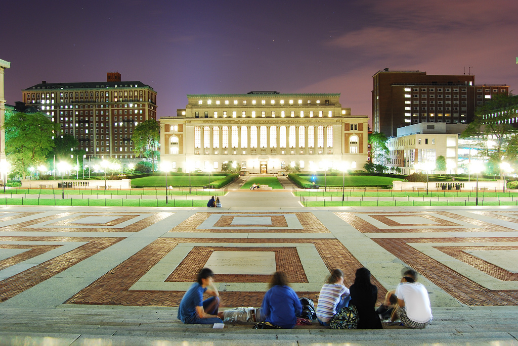 A group of Columbia University students sit along the steps of Low Memorial Library in the campus's central plaza. 