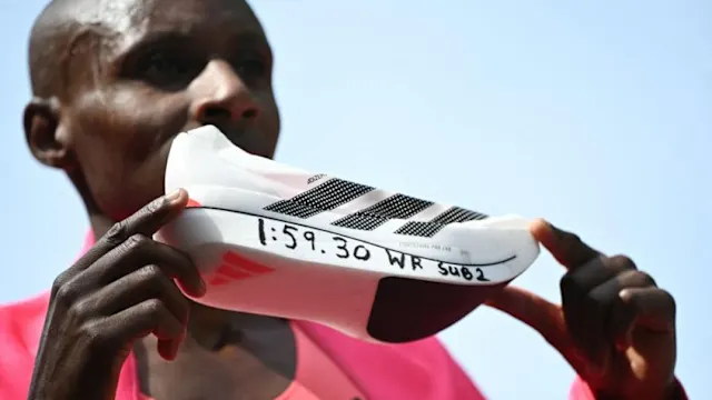 Sebastian Sawe holding up the Adizero Adios Pro Evo3 with his mile time.2